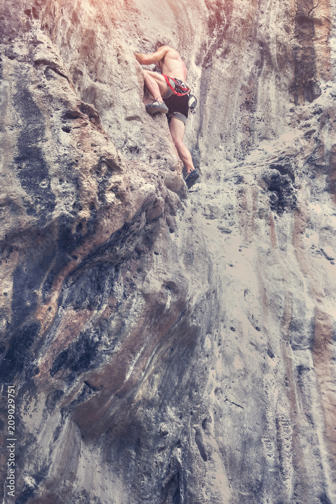 Obraz premium A young man climbs the cliff. Adrenaline, risk, ambition