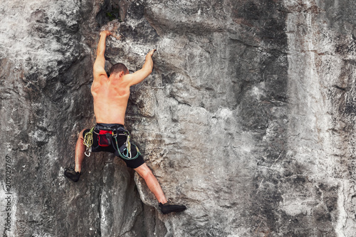 A man clambering over a rock without a safety rope