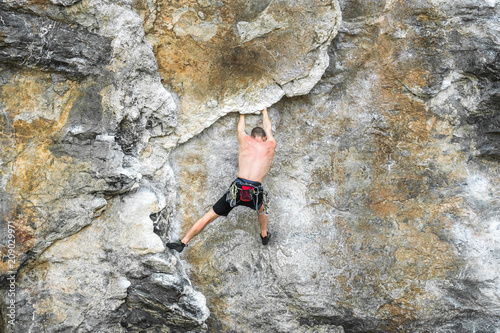 Young male mountaineer climbing a cliff without safety equipment