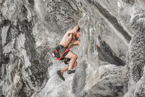 Young bearded male mountaineer climbing a cliff
