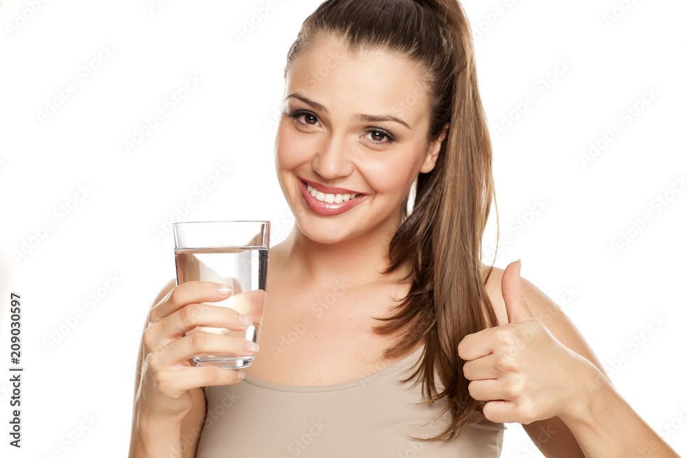 happy woman holds a glass with water and showing thumbs up on white background happy woman holds a glass with water and showing thumbs up on white background