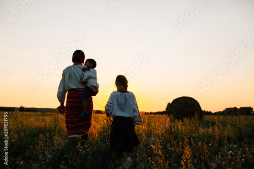 Family: mother and son and daughter are walking along the field. They are dressed in embroidered robes.