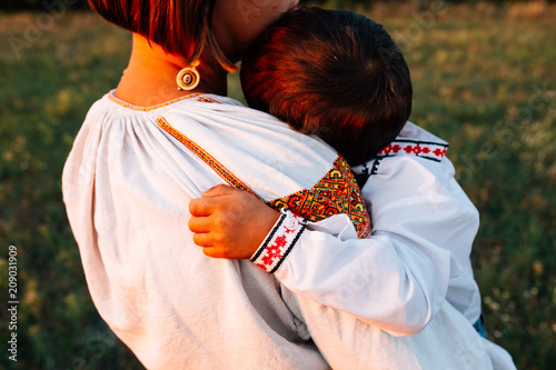 Family: mother carries a boy. They are dressed in embroidered robes.