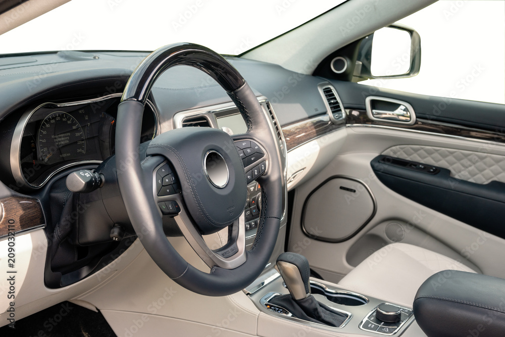 Car dashboard and steering wheel. The interior of a modern luxury SUV type car.Kokpit trimmed with leather and decorated with precious wood