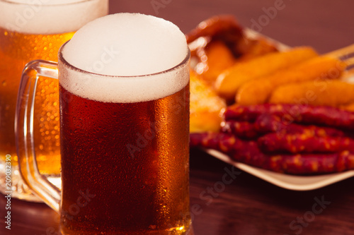 Traditional German food Oktoberfest. Beer, baked chicken wings, popcorn, assortment of different sausages homemade bretzels.