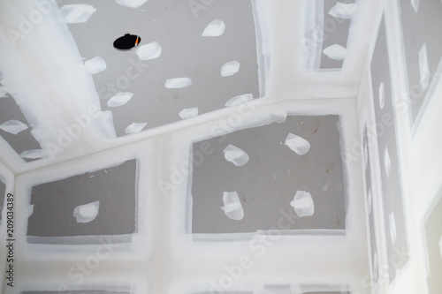 Empty room interior new ceiling plaster gypsum board with drill hole for lamp in construction site.