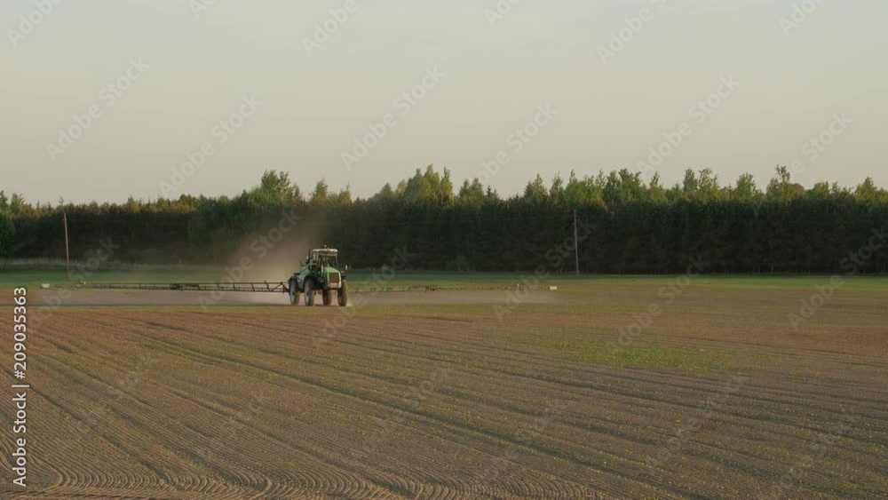 Tractor spray fertilize field with chemicals for crop plants protection from weed and pest.