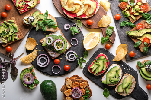 Delicious toasts with avocado on slate plates and boards