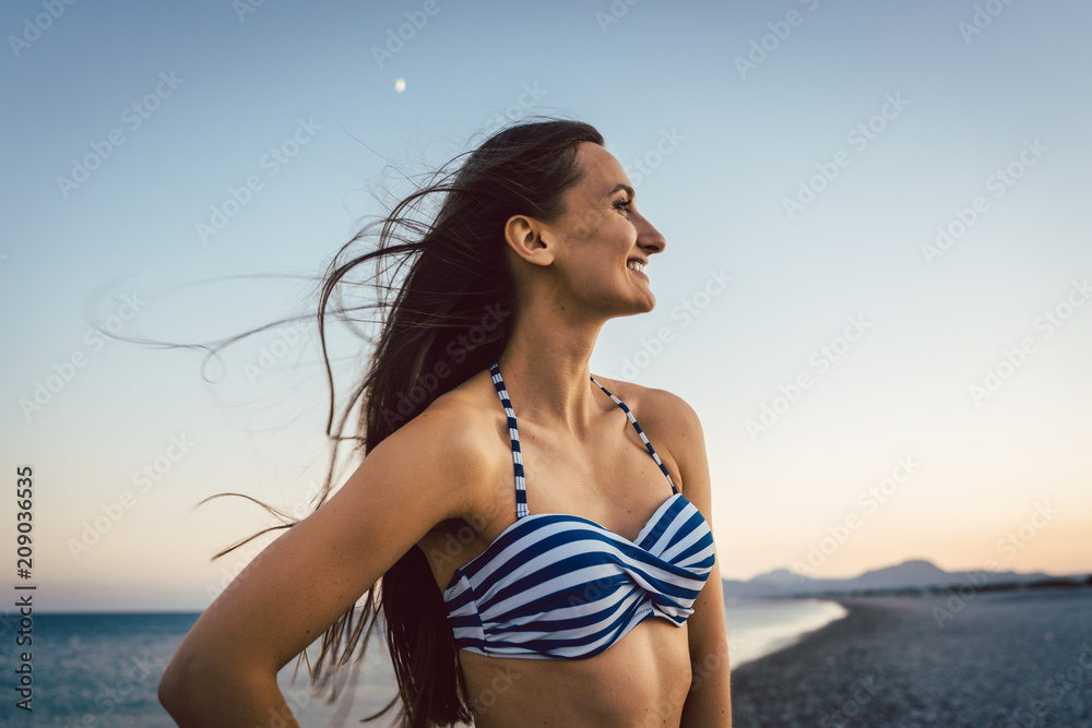 Woman having a great time on the pebble beach after sunset Woman having a great time on the pebble beach after sunset