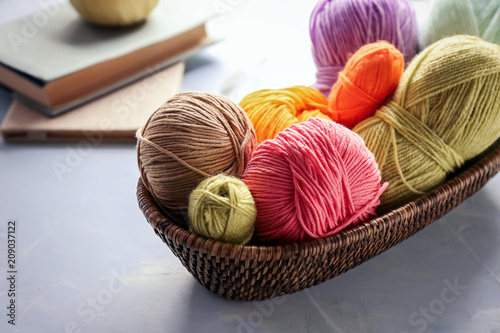 Wicker basket with knitting yarn on table