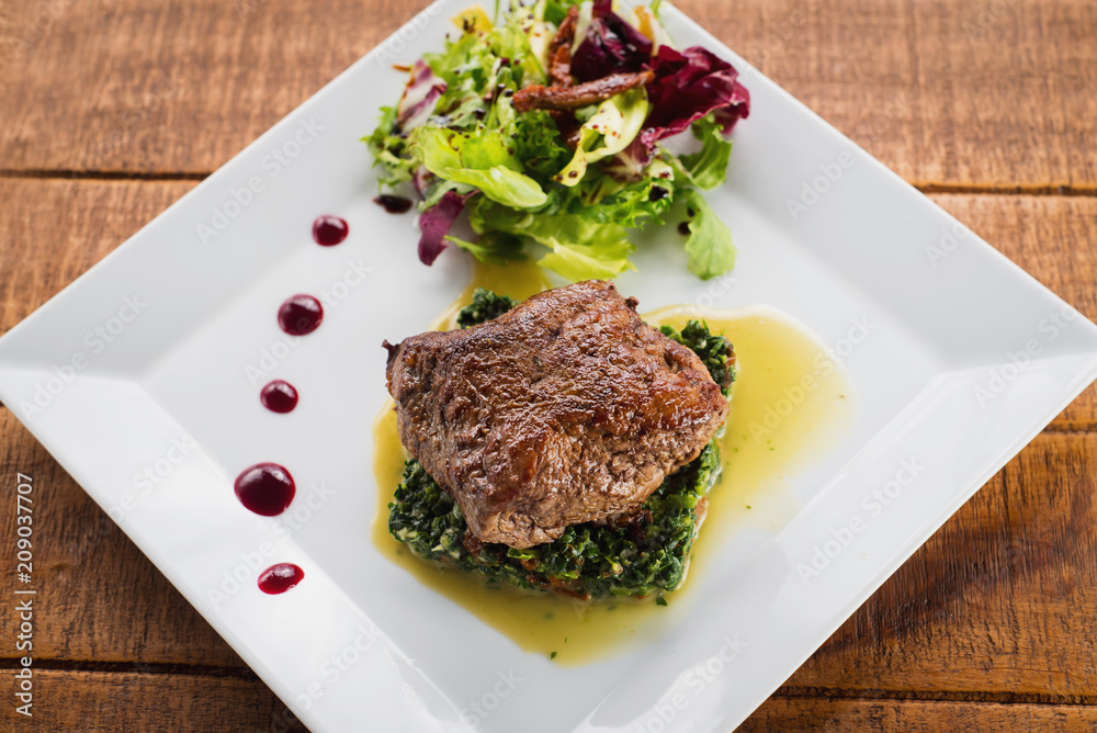 Fried piece of meat with herbs and spices on wooden background Fried piece of meat with herbs and spices on wooden background