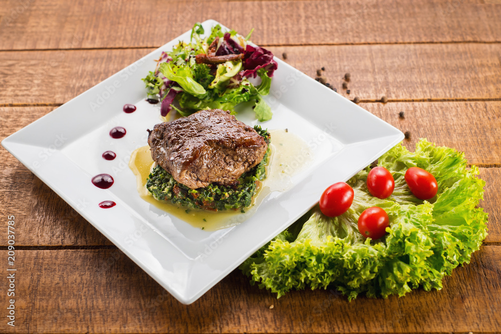 Fried piece of meat with herbs and spices on wooden background