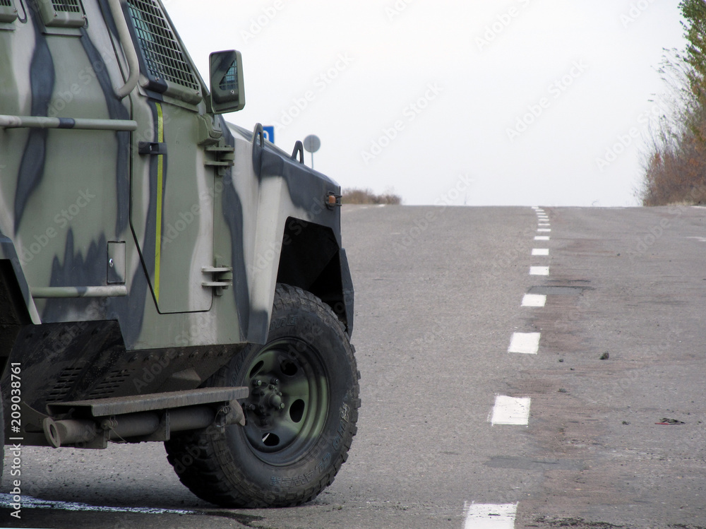 The front of an armored military SUV standing on the road, close-up. Road to Donbass war