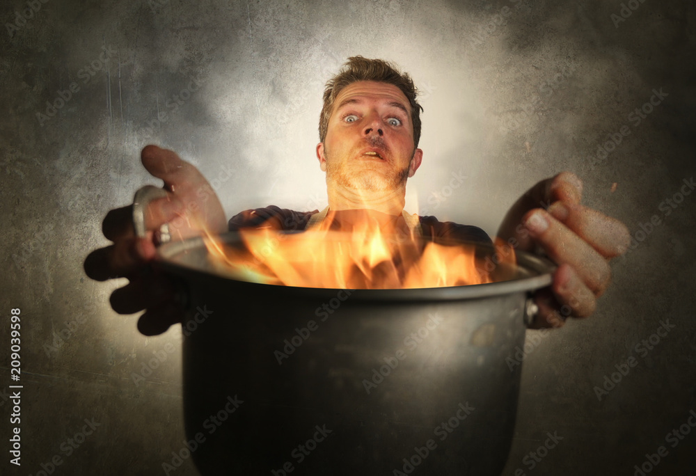 young attractive and shocked messy home cook man with apron holding