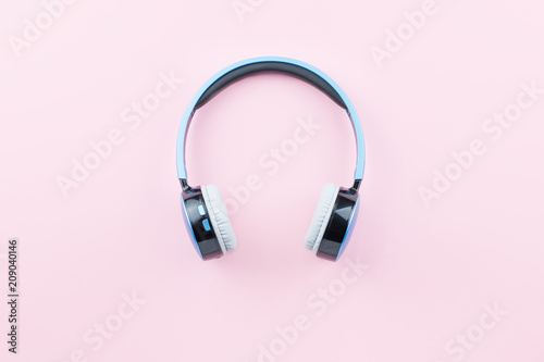 Blue wireless headphones close up on pastel pink background. Flat lay, top view