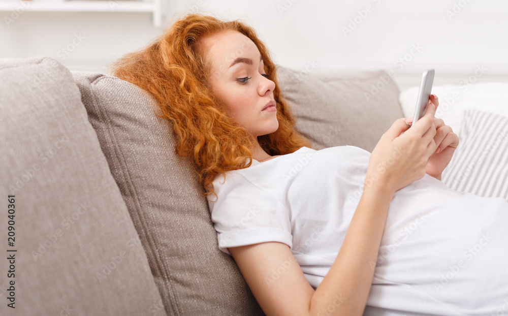 Pensive young girl texting on smartphone