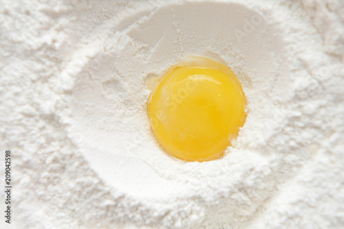 Bright and beautiful egg yolk in wheat flour close-up