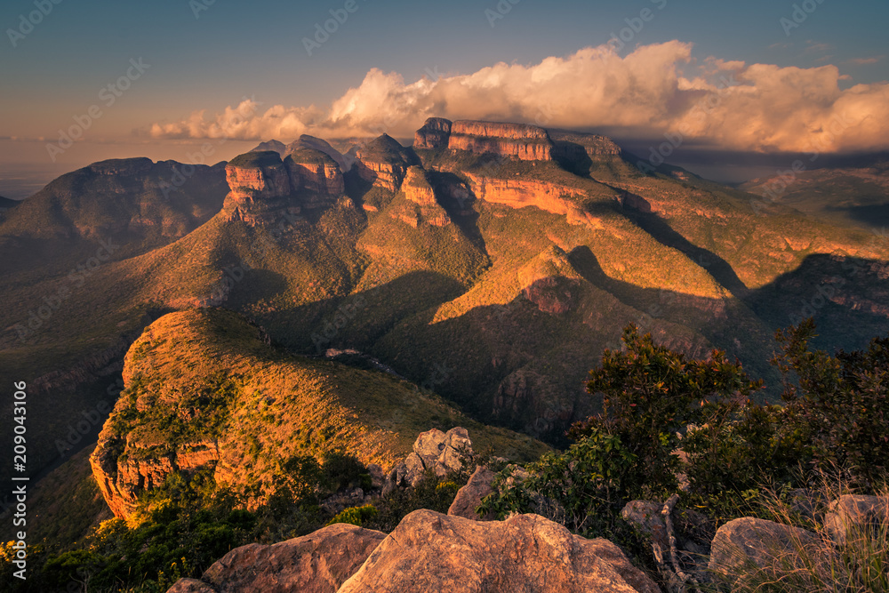 Obraz premium A wide shot of the Three Rondavels and surrounding landscape lit up with dramatic texture and form at sunset golden hour. Mpumalanga, South Africa