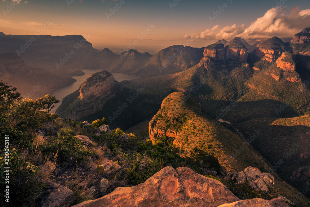Wide high-angle view of the Three Rondavels and Blyde River Canyon in delicate warm tones at Sunset Golden Hour. Mpumalanga, South Africa