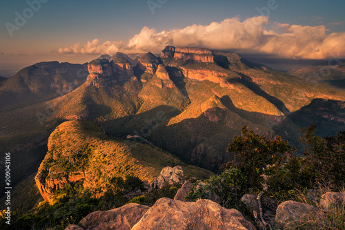 A wide shot of the Three Rondavels and surrounding landscape lit up with dramatic texture and form at sunset golden hour. Mpumalanga, South Africa © Jennifer