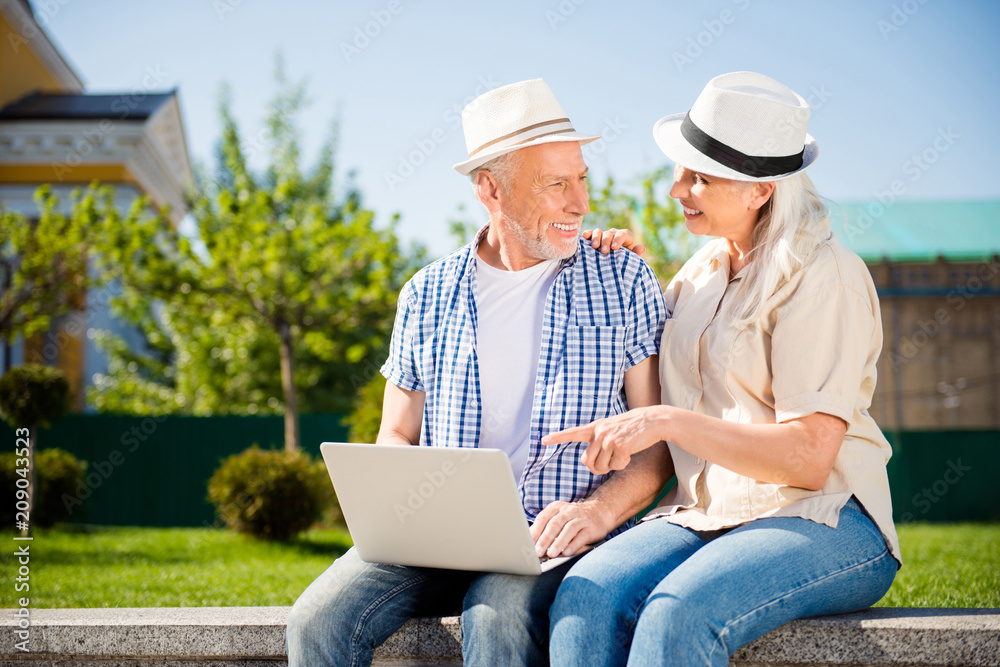 Portrait of positive cheerful couple using laptop making online shopping choosing tour for holidays charming woman showing screen of computer with forefinger. Customer buyer buy purchase concept