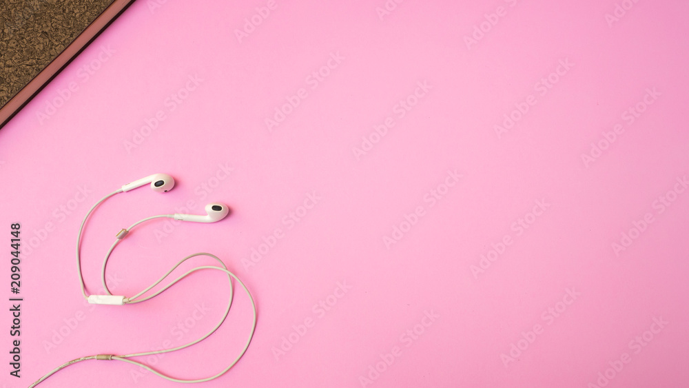 Earphones and notebook on pink  background. Pastel color Minimal concept Copy space