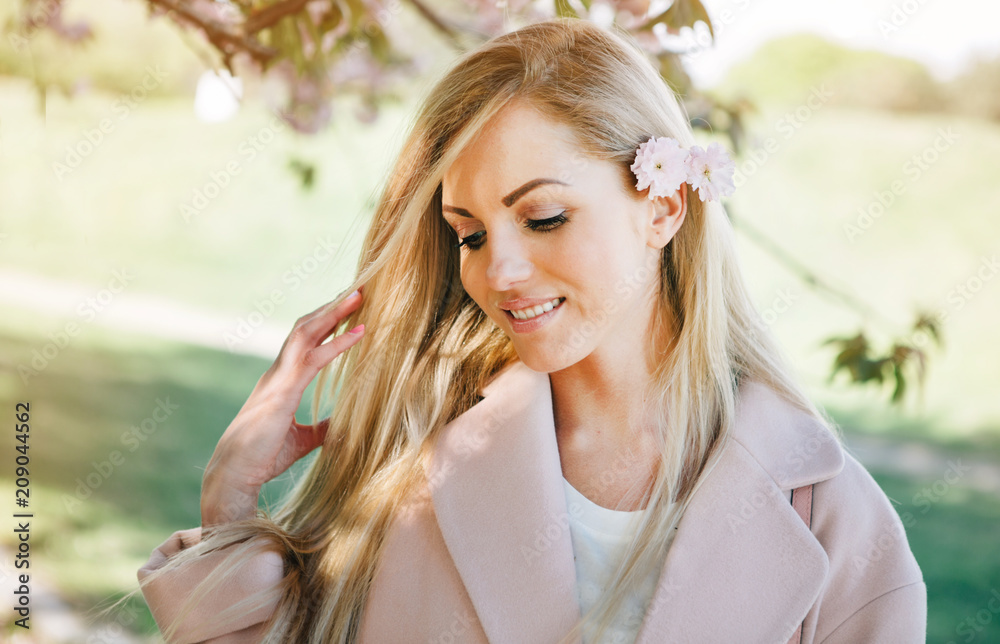 Woman with long blond hair in the garden with flowers. Beautiful girl on a sunny day. Woman with long blond hair in the garden with flowers. Beautiful girl on a sunny day.