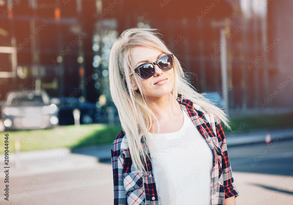 Beautiful blond young woman walking on the city street.