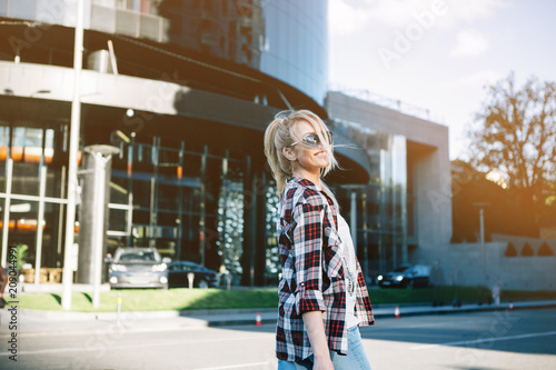 Beautiful blond young woman walking on the city street.
