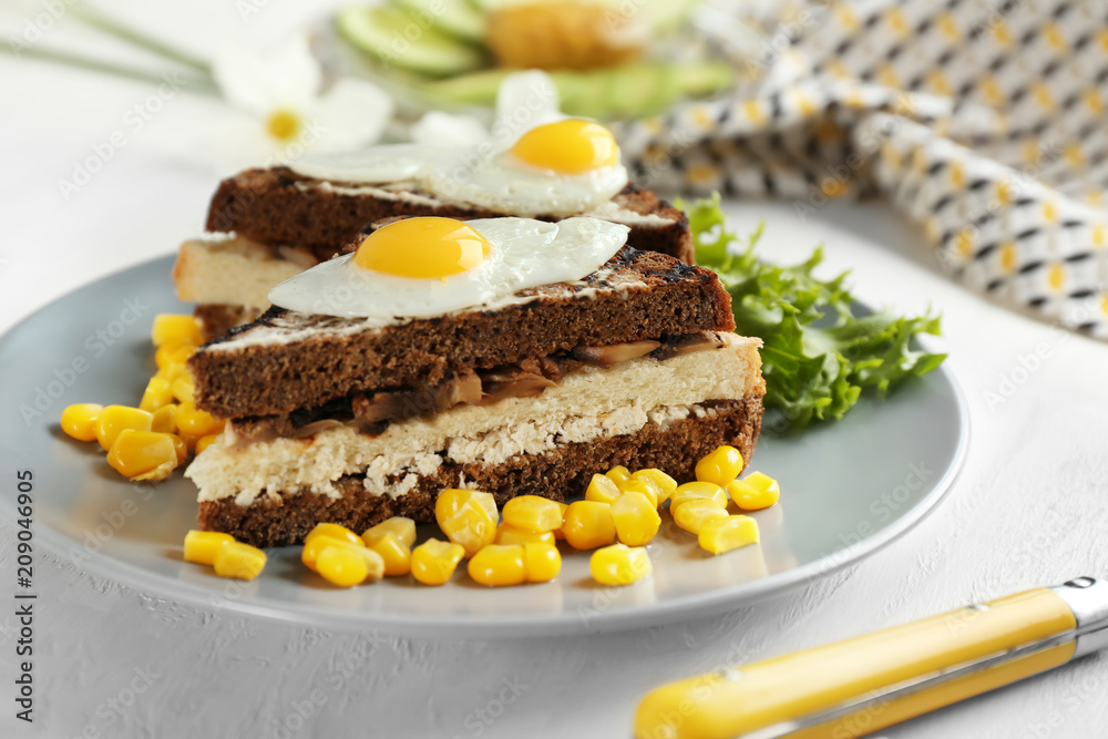 Plate with toasted bread, fried eggs and corn kernels on table