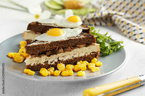 Plate with toasted bread  fried eggs and corn kernels on table