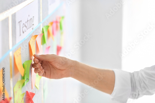 Man with sticker near scrum task board in office