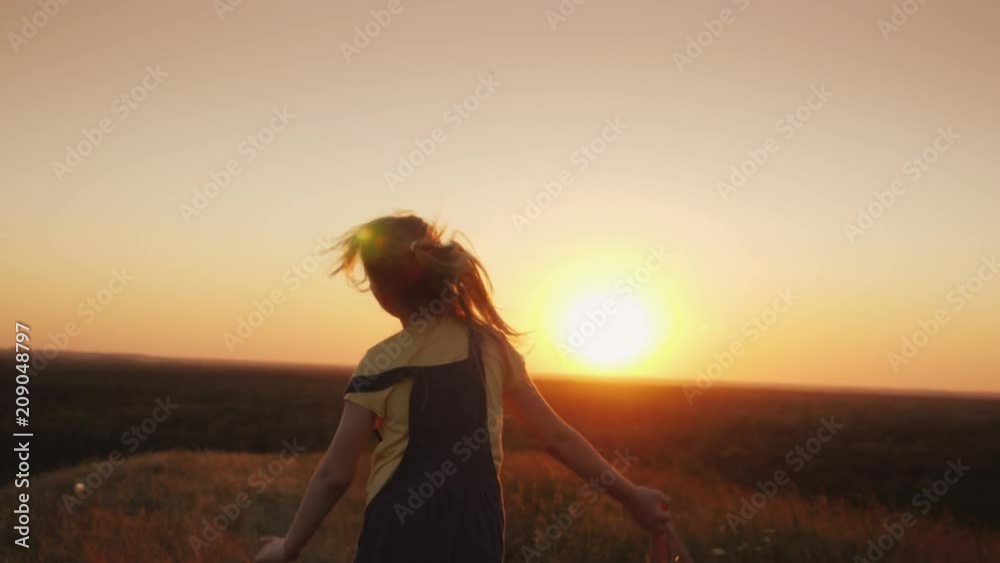 A happy child is waving a backpack and running towards the sun. Summer Holidays Concept A happy child is waving a backpack and running towards the sun. Summer Holidays Concept
