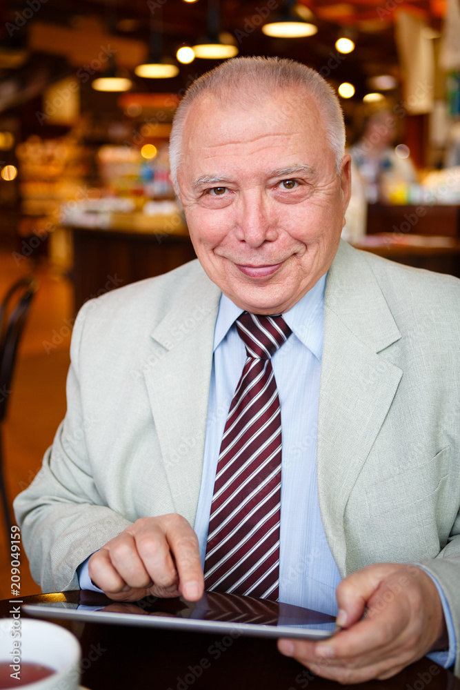 business, technology and people concept - old senior businessman with tablet pc computer drinking coffee in lunch time business, technology and people concept - old senior businessman with tablet pc computer drinking coffee in lunch time