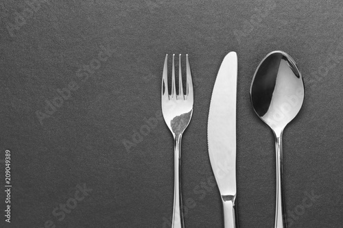 knife fork and spoon on black table, top view.