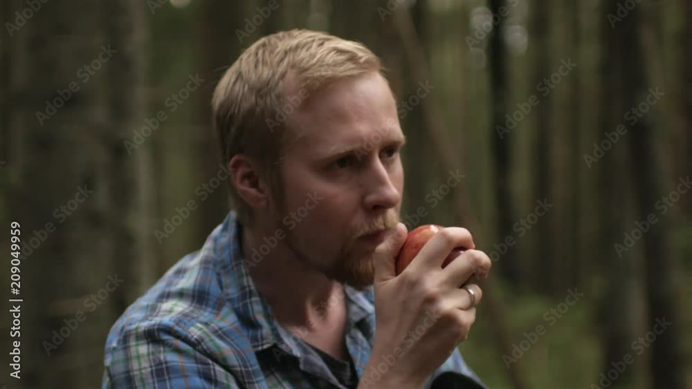 man eating an apple in the forest man eating an apple in the forest