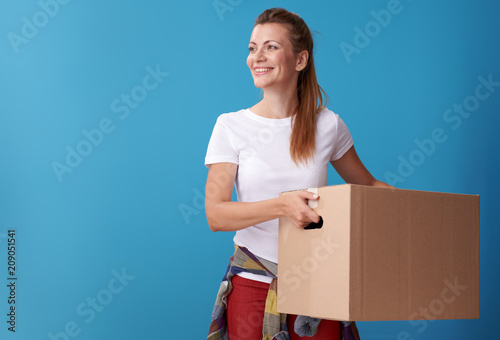 smiling woman with cardboard box looking at copy space on blue