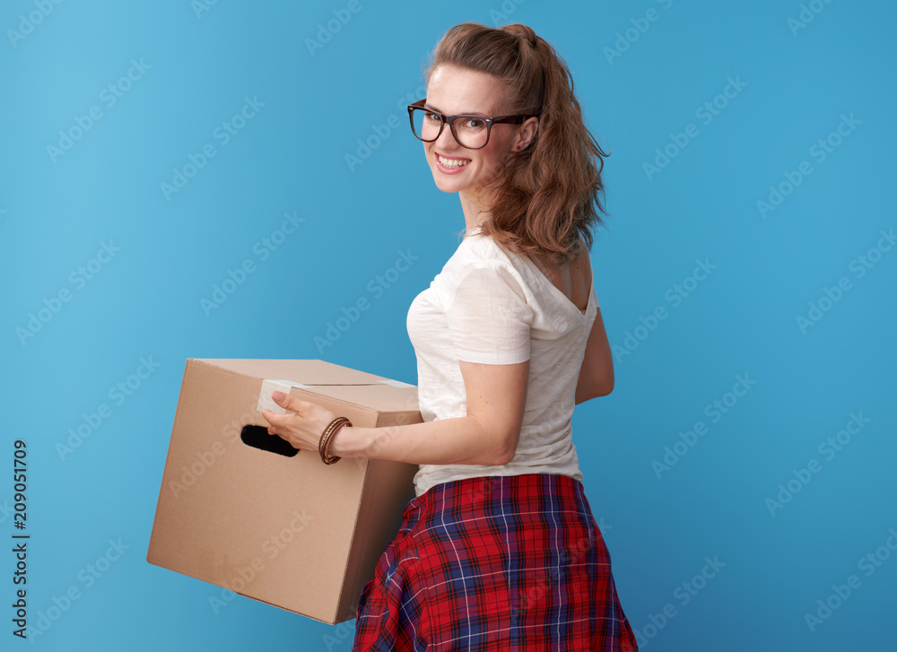 happy active hipster with cardboard box looking back on blue happy active hipster with cardboard box looking back on blue