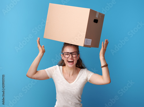 happy active hipster with cardboard box on head on blue