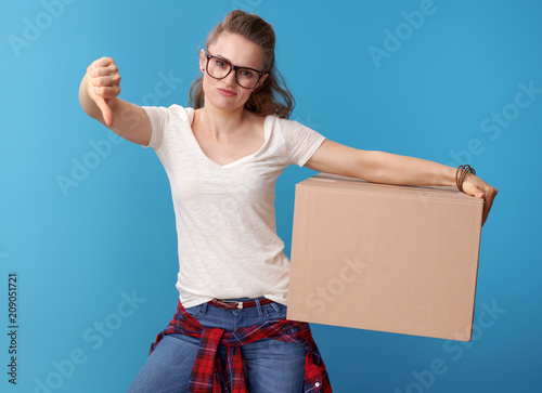 Принти на полотні unhappy hipster with cardboard box showing thumbs down on blue