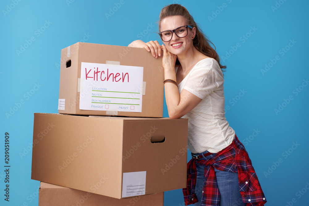 smiling woman lean against cardboard boxes on blue smiling woman lean against cardboard boxes on blue
