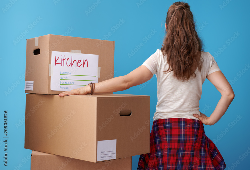modern woman standing next to cardboard boxes on blue