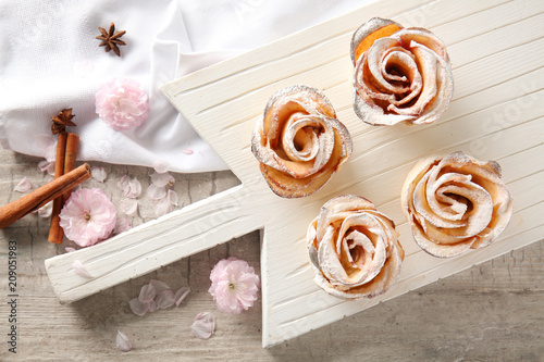 Tasty apple roses from puff pastry on wooden board