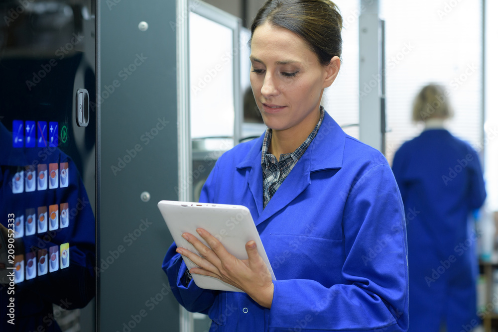 technician holding digital tablet while examining server in server room