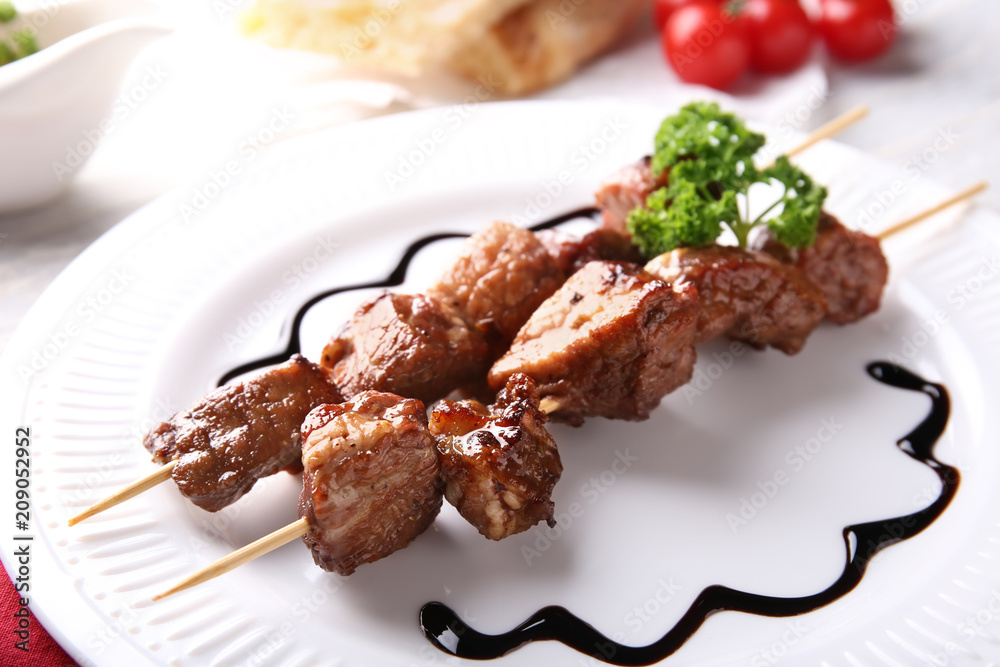 Barbecue skewers with juicy meat and sauce on plate, closeup