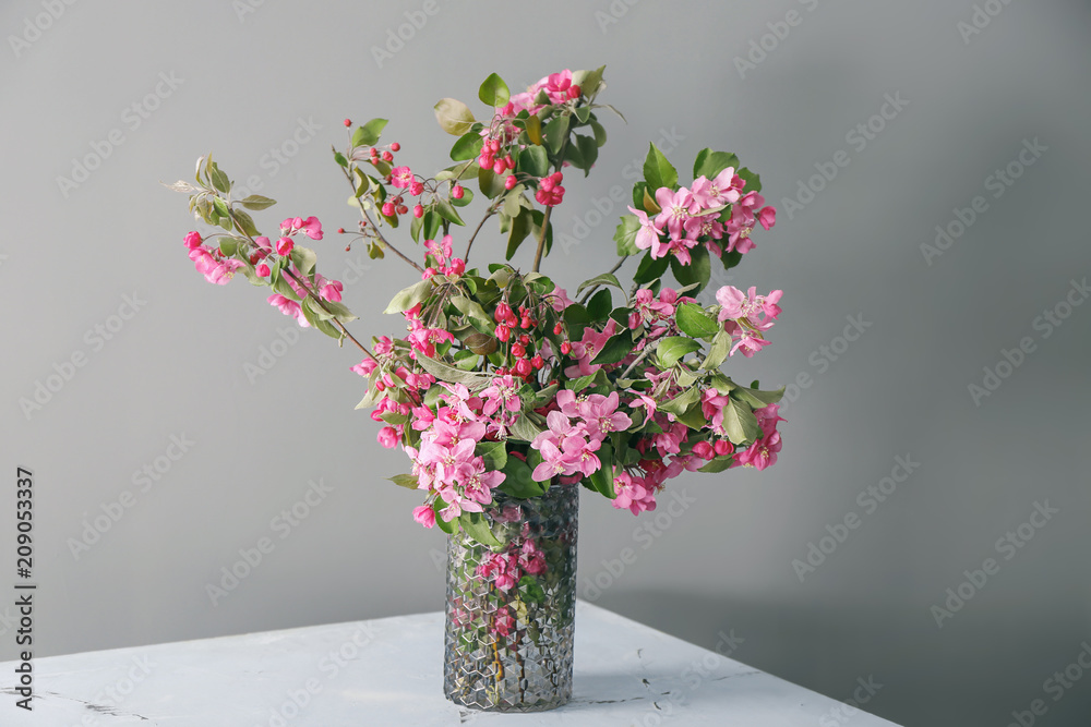 Naklejka premium Vase with beautiful blossoming branches on grey background