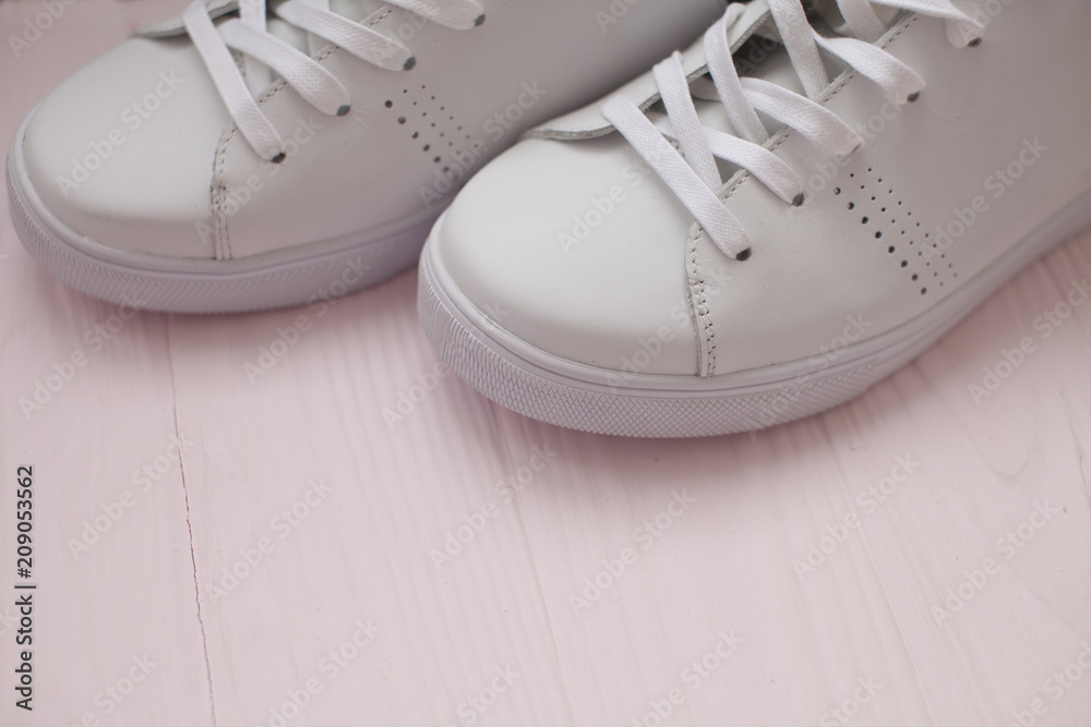 White sneakers on light pink background.Toned image. Women's shoes. stylish white sneakers