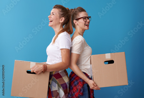 female roommates with a cardboard boxes standing back to back