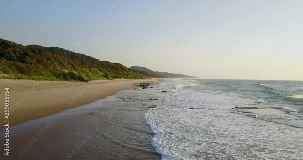 Waves crashing on rocks on a sandy tropical beach Waves crashing on rocks on a sandy tropical beach