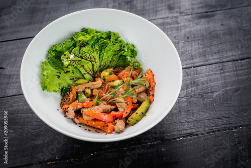 Salad from meat with red pepper and soy sauce on wooden background